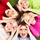 Uśmiechnięte przedszkolaki leżące na plecach w kółku, patrzące w obiektyw.