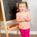 Dziewczynka stojąca przy tablicy ucząca się pisać.