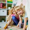 Dwie dziewczynki w przedszkolu bawiące się w namiocie.