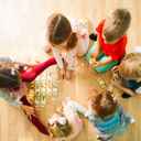 Dzieci w żłobku siedzące na ziemi i bawiące się kartami.