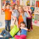 Uśmiechnięte dzieci ściskające panią przedszkolankę i machające do obiektywu.